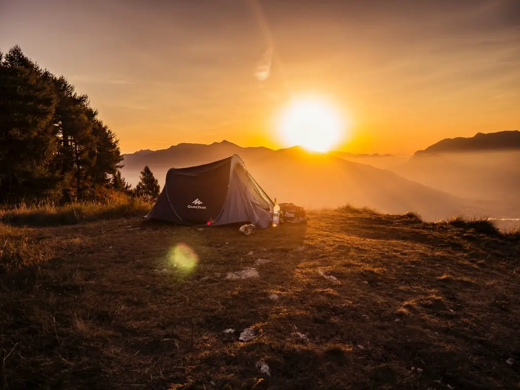 dome tent on mountain top with sun as background sleep outside outdoors