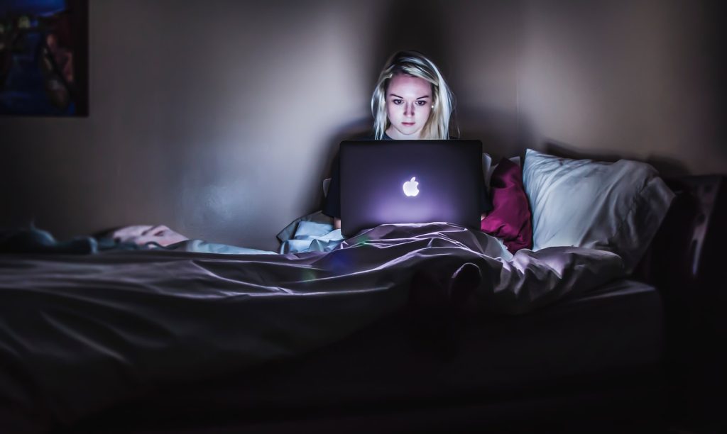 woman sitting on bed with MacBook on lap Pulling an all-nighter