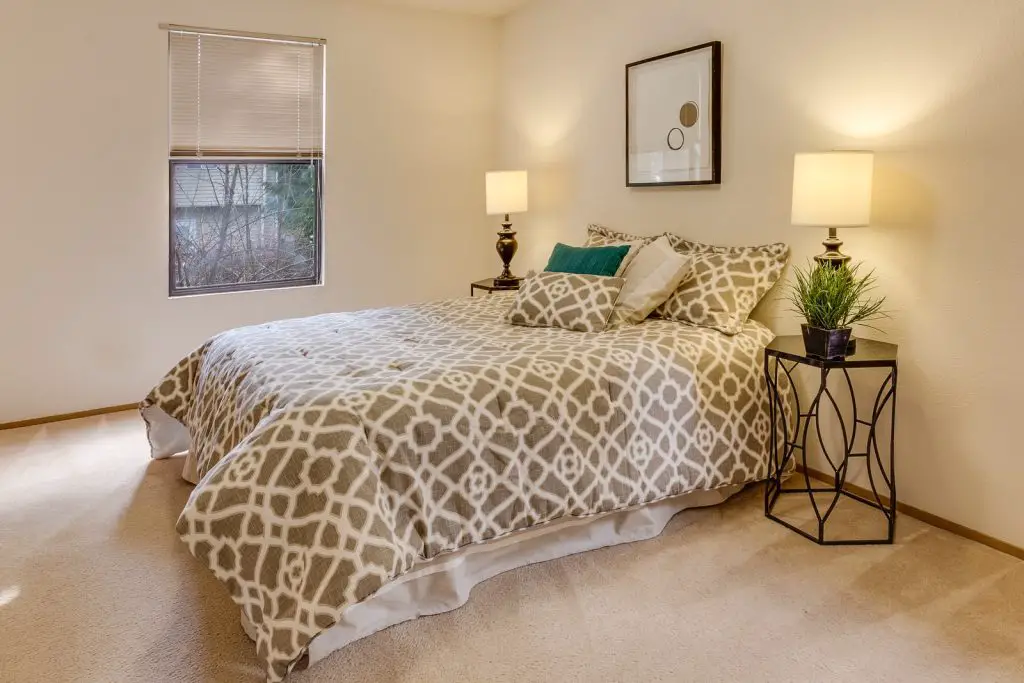 How to Put a Bed Against the Wall (The Right Way) 2 white-and-brown quatrefoil bedspread set on bed near window against the wall