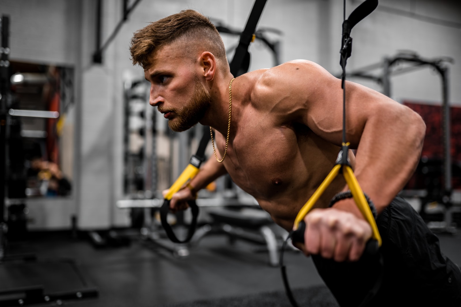 topless muscle man in black pants holding black and yellow exercise equipment