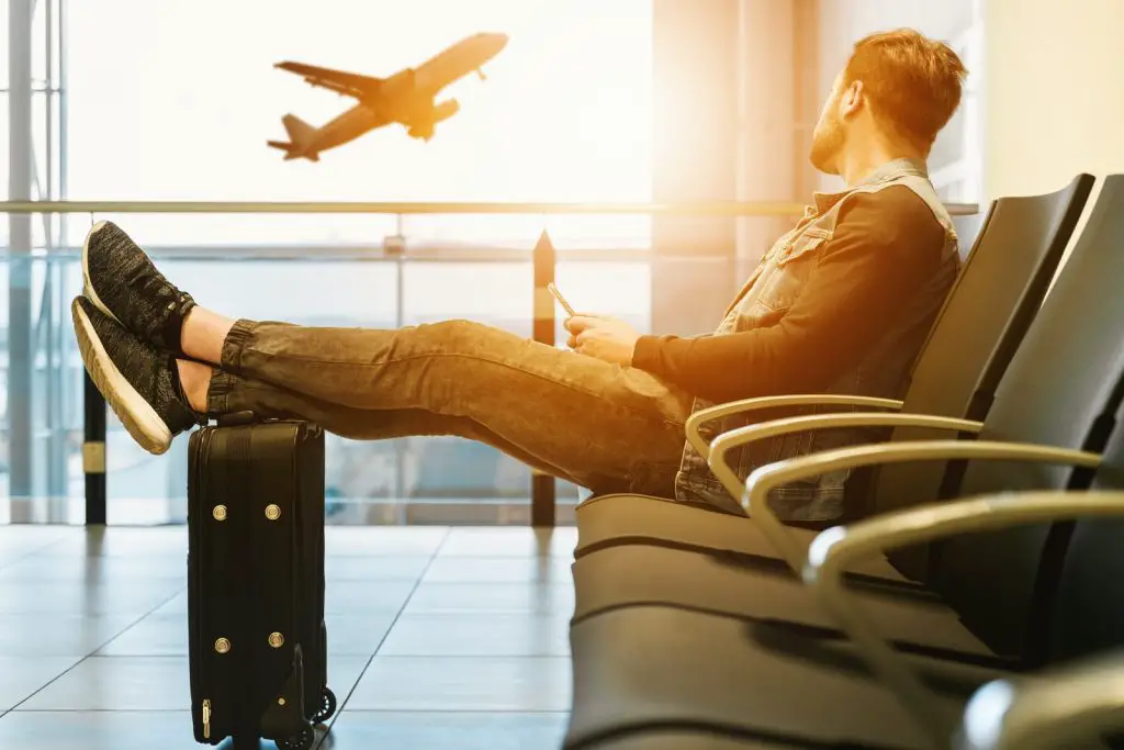What Is a Good Circadian Rhythm - And Why Is It Important? 2 man sitting on gang chair with feet on luggage looking at airplane