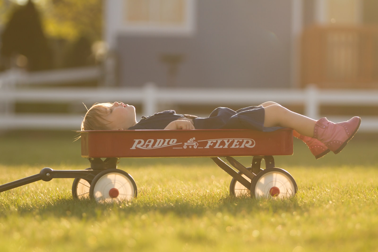 napping boy on red Radio Flyer during daytime