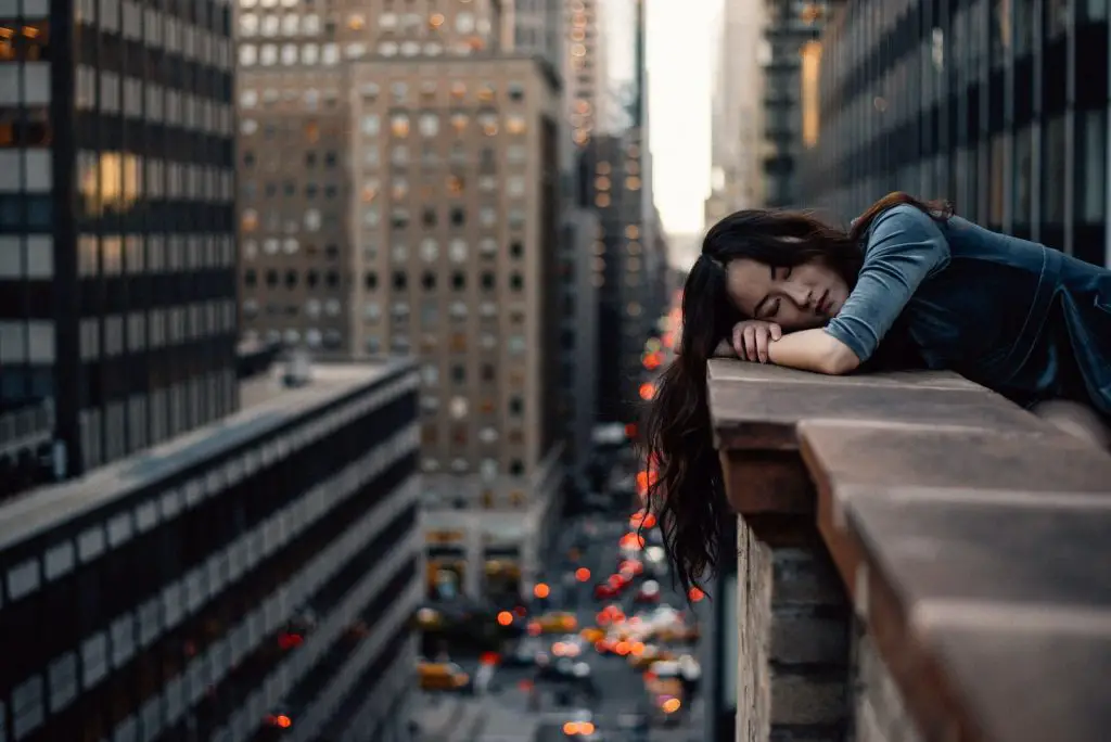 woman sleeping on top building rail during daytime heavy sleeper