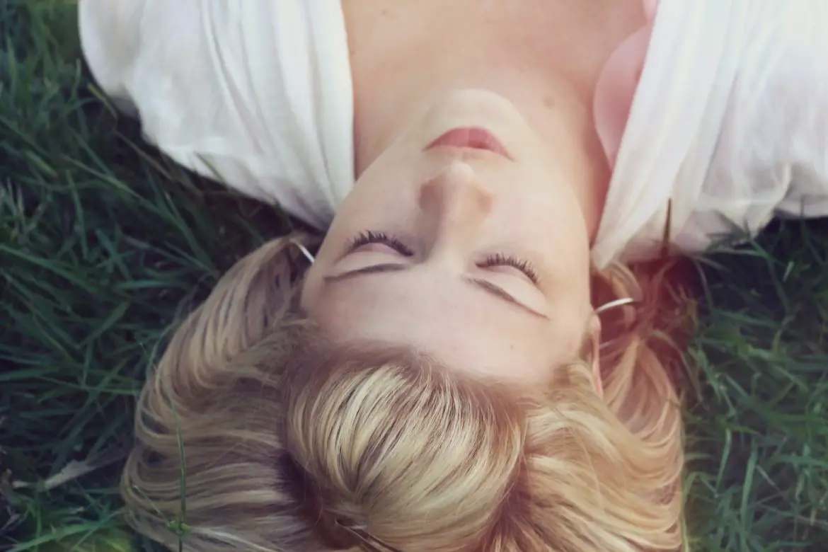 woman lying on green grasses become light sleeper