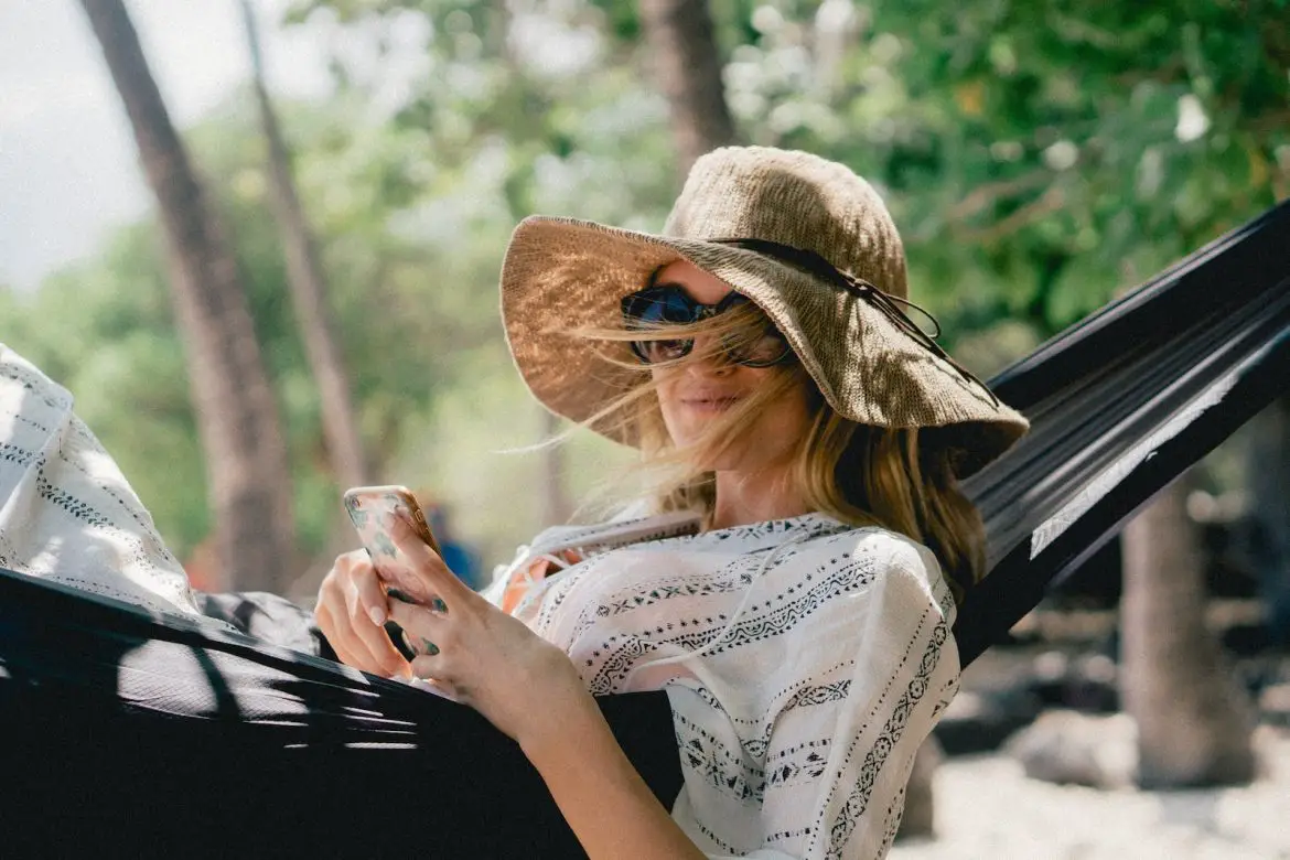 woman resting lying on black hammock while holding phone - doing nothing
