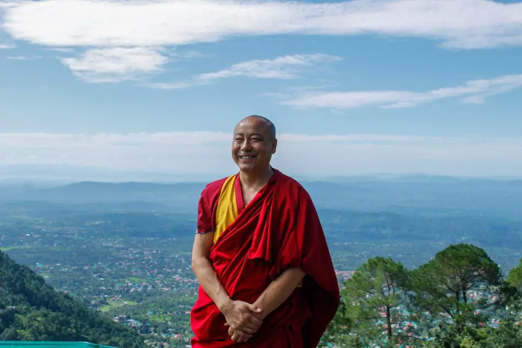 How Long Do Monks Meditate? - Practice, Hours, and Life of a Monk 2 monk in red and yellow shirt sitting on green grass field during daytime