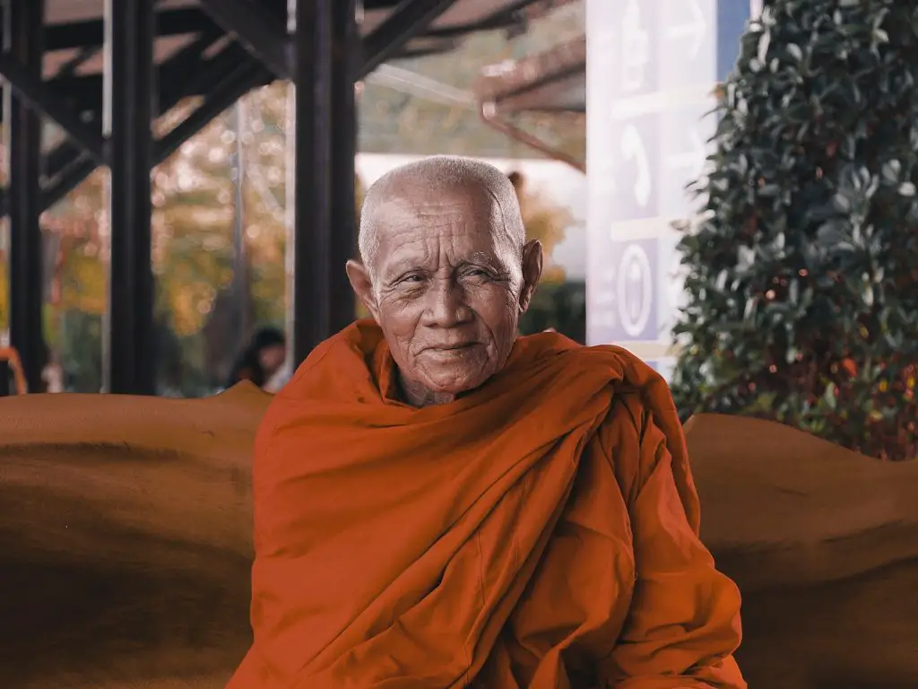 man wearing orange shirt sitting on bench monk how long sleep
