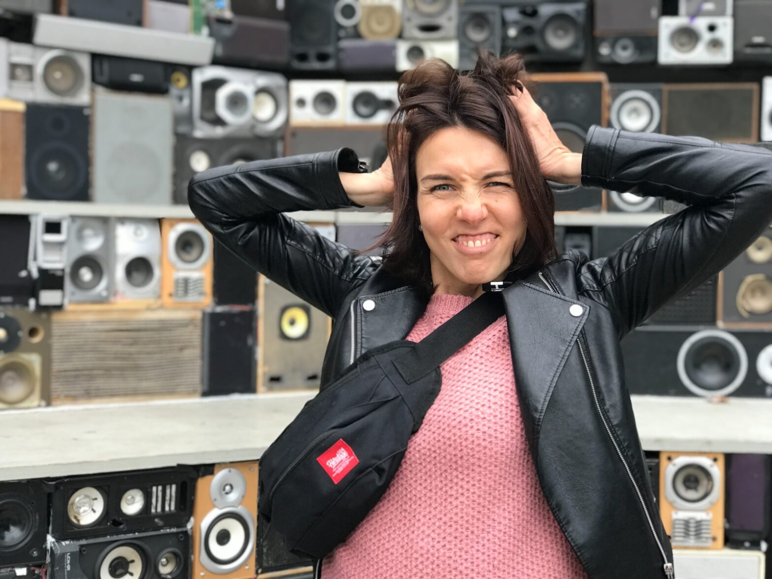 an excited woman standing in front of a wall of speakers
