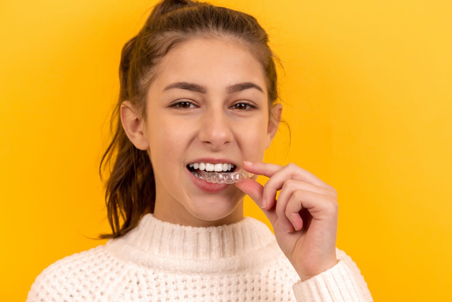 smiling woman in white knit sweater.how to sleep with retainers