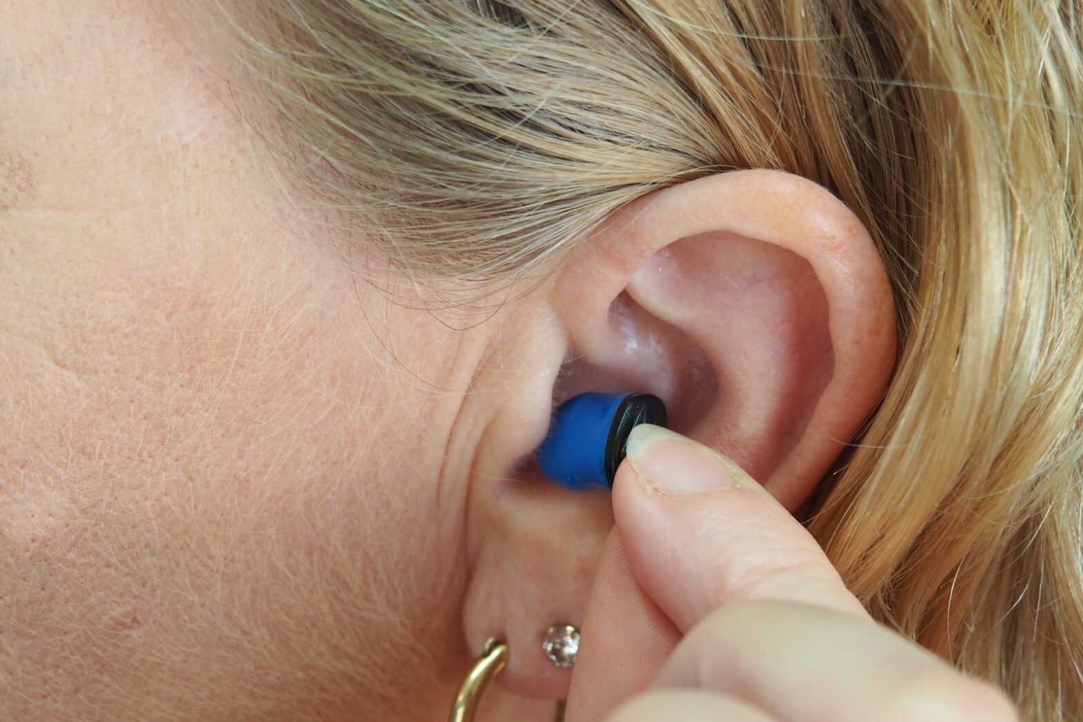 woman wearing blue stud earring. should you sleep on the side of a ruptured eardrum