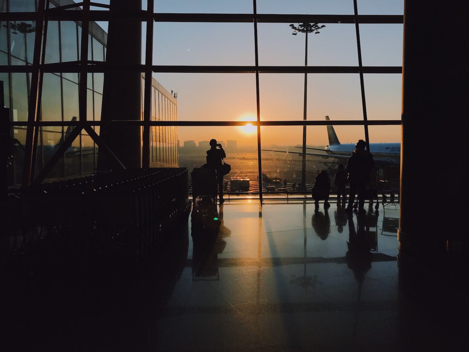 silhouette of people standing inside jfk airport during golden hour